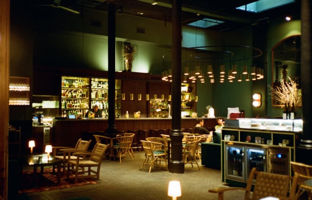 A sophisticated bar with circular lighting fixtures and rattan chairs
