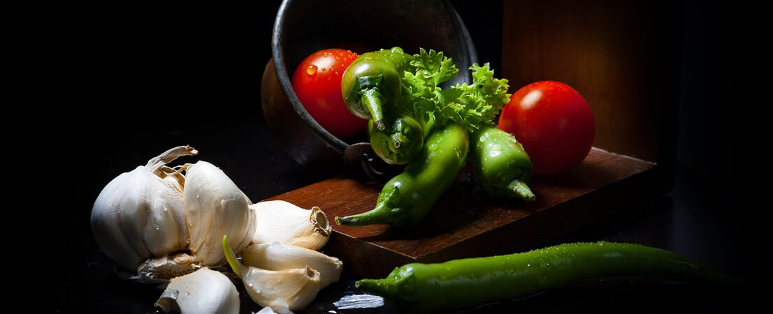 fresh vegetables with tomatoes, garlic, and green chilies on a wooden board