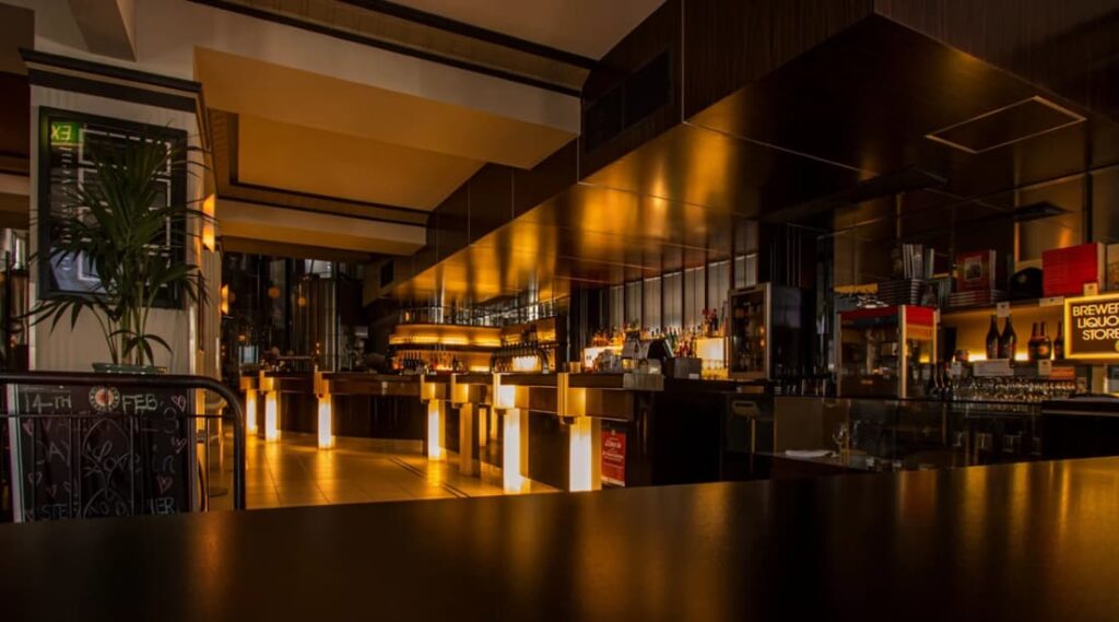 A dimly lit, modern bar area with ambient lighting and high stools