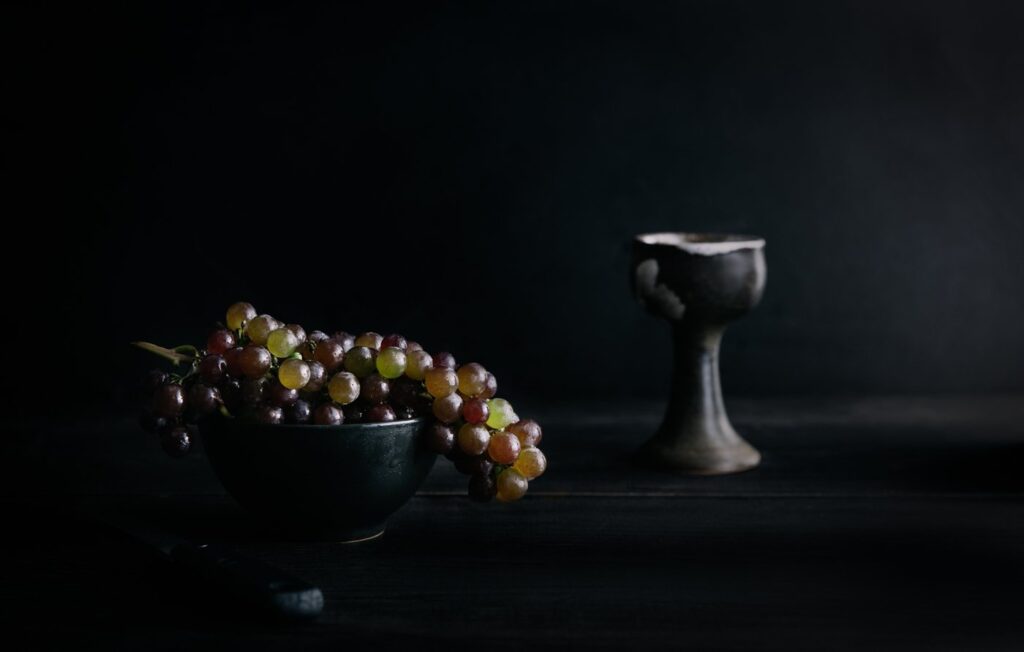 a goblet and a vase of grapes on the table