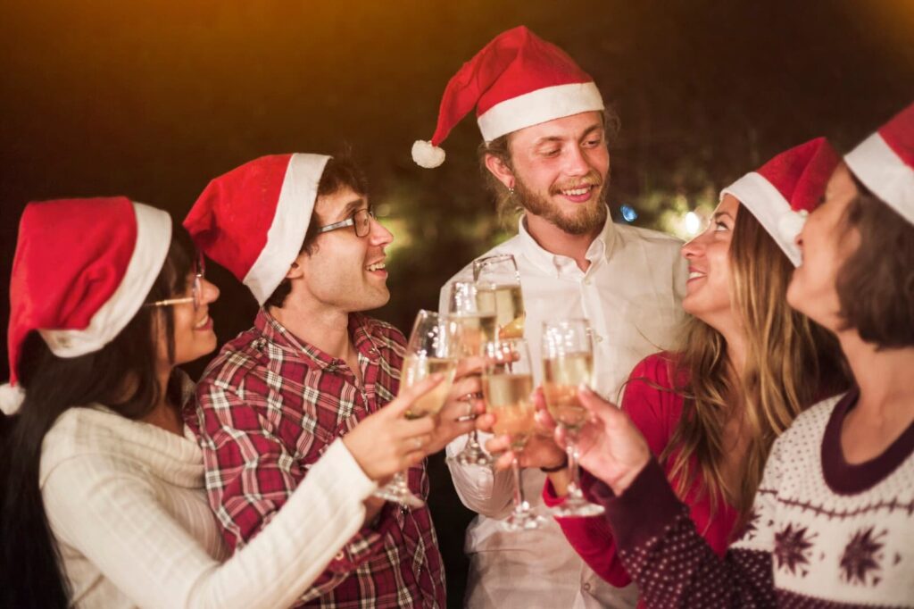 Friends in Santa hats clinking glasses at party