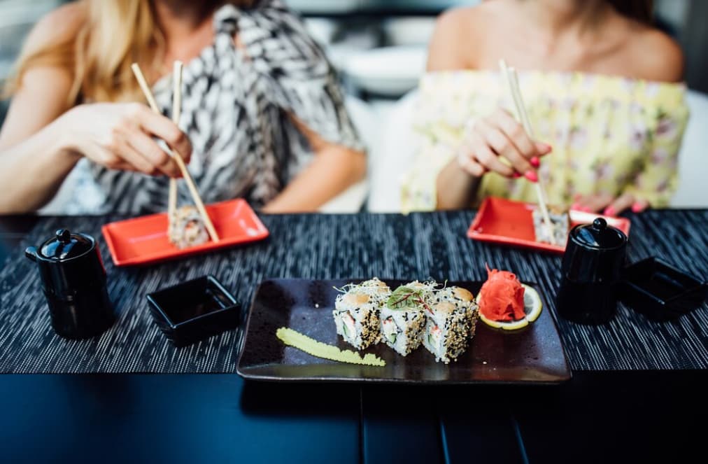 Two people eating sushi, focusing on their hands and the food