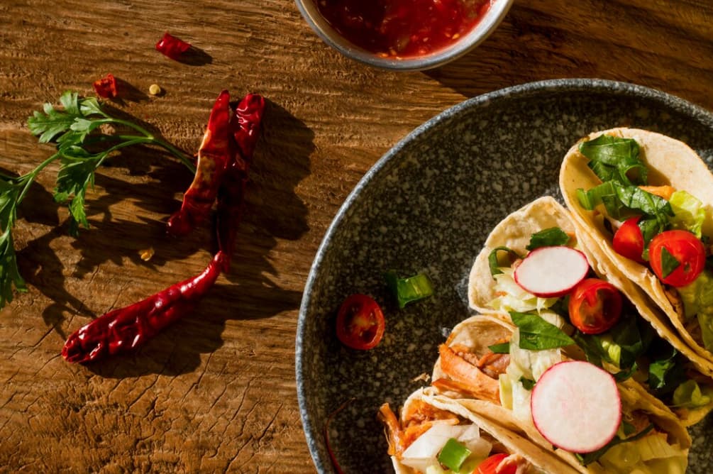 A rustic plate of tacos with fresh toppings on a wooden surface