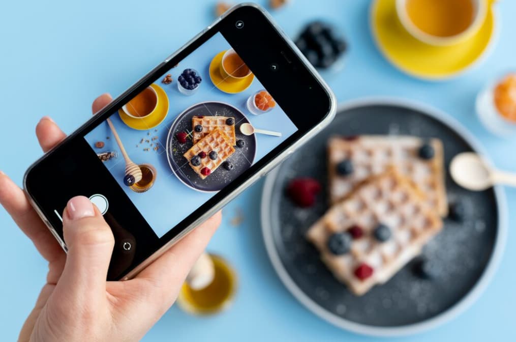 A person taking a photo of a waffle breakfast with a smartphone