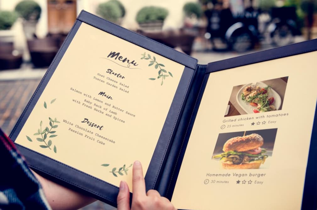 A person holding a menu featuring starters, main courses, and desserts