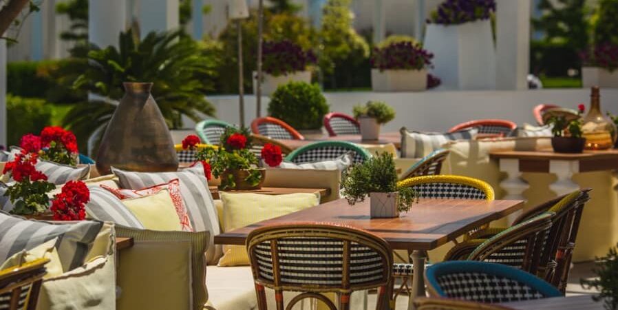 A cozy outdoor cafe setting with vibrant flowers and plush cushions