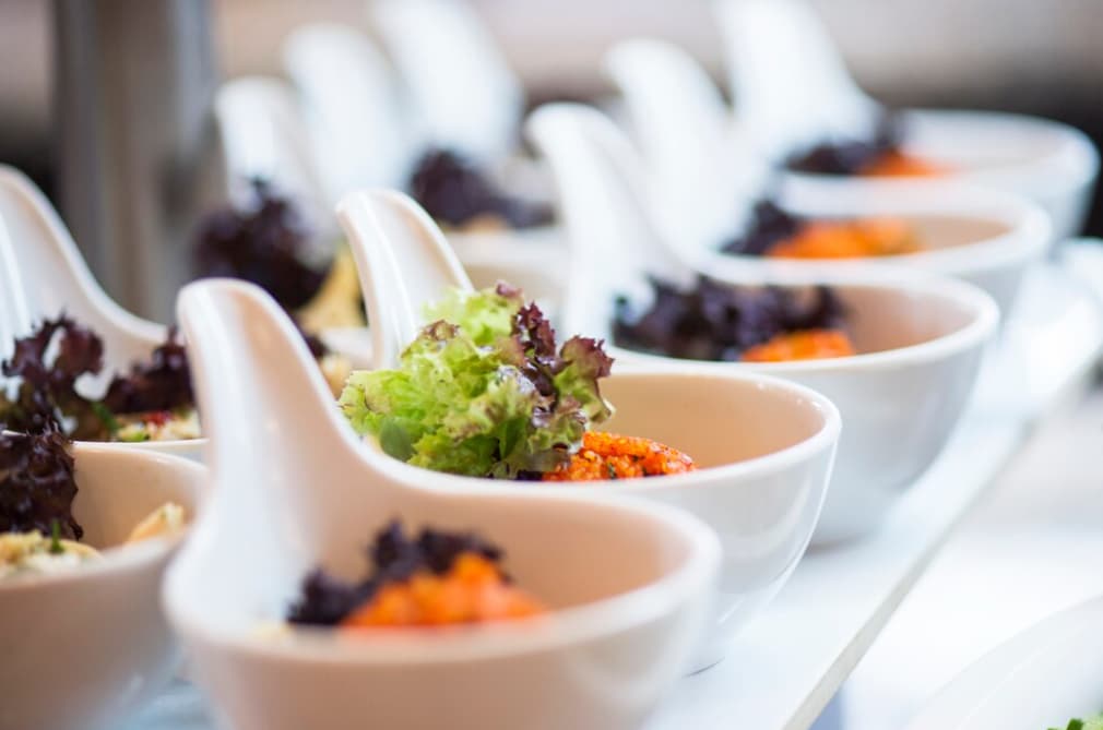 Elegant white serving bowls filled with salad on a buffet table