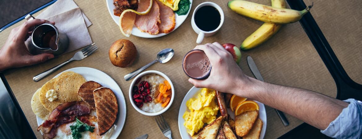 table set for continental breakfast hands of men and women holding coffee mugs