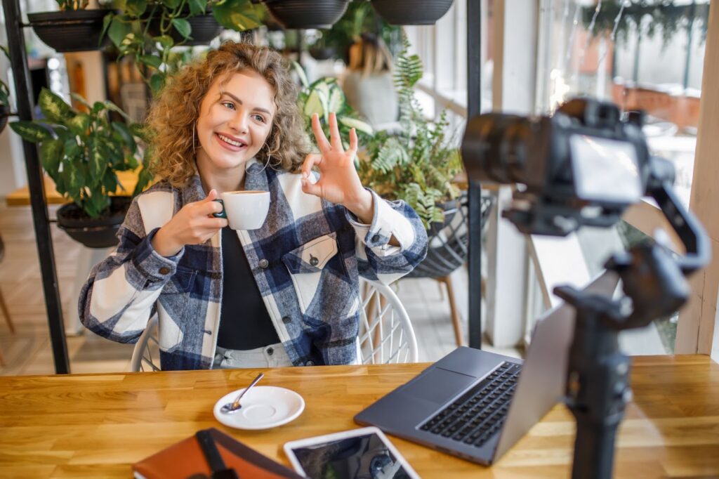 Smiling blogger posing to the camera with cup of coffee