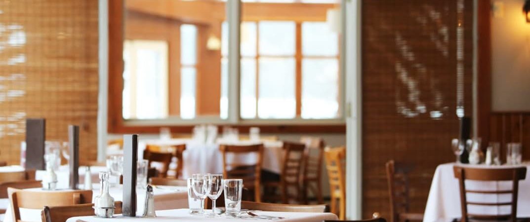 A well-lit, casual dining restaurant with empty tables set for service