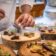 A chef is plating a dish on wood slices with dry ice smoke