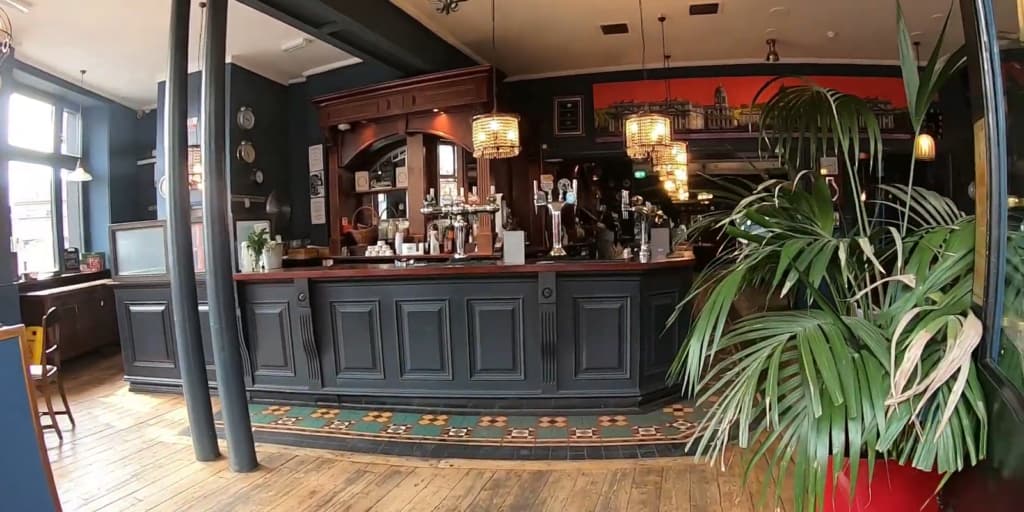 An empty bar with blue walls, wood floors, and a classic bar counter
