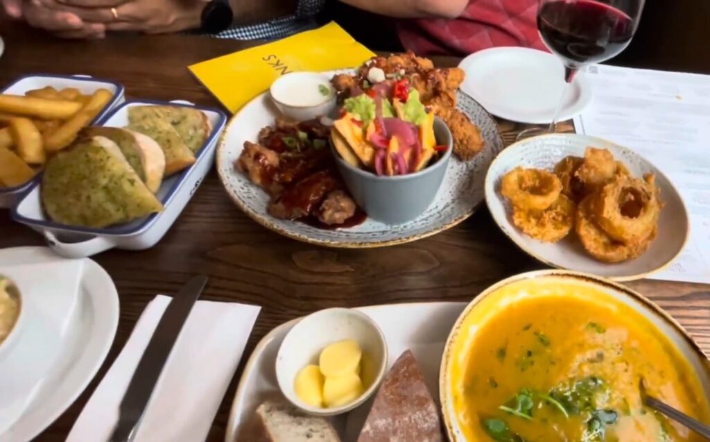 A table with various dishes and a glass of wine, ready to eat