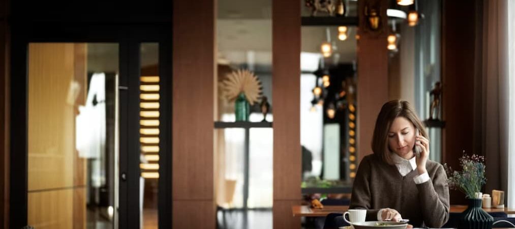 woman sitting in the restaurant and speaking on the phone over her dishes