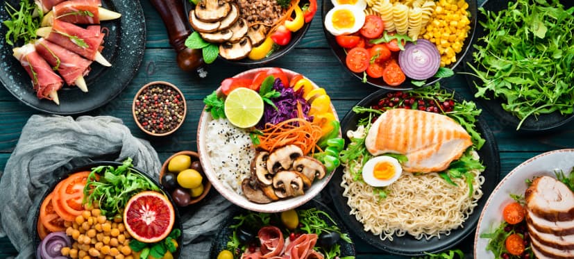A variety of colorful, healthy dishes spread on a dark wooden table