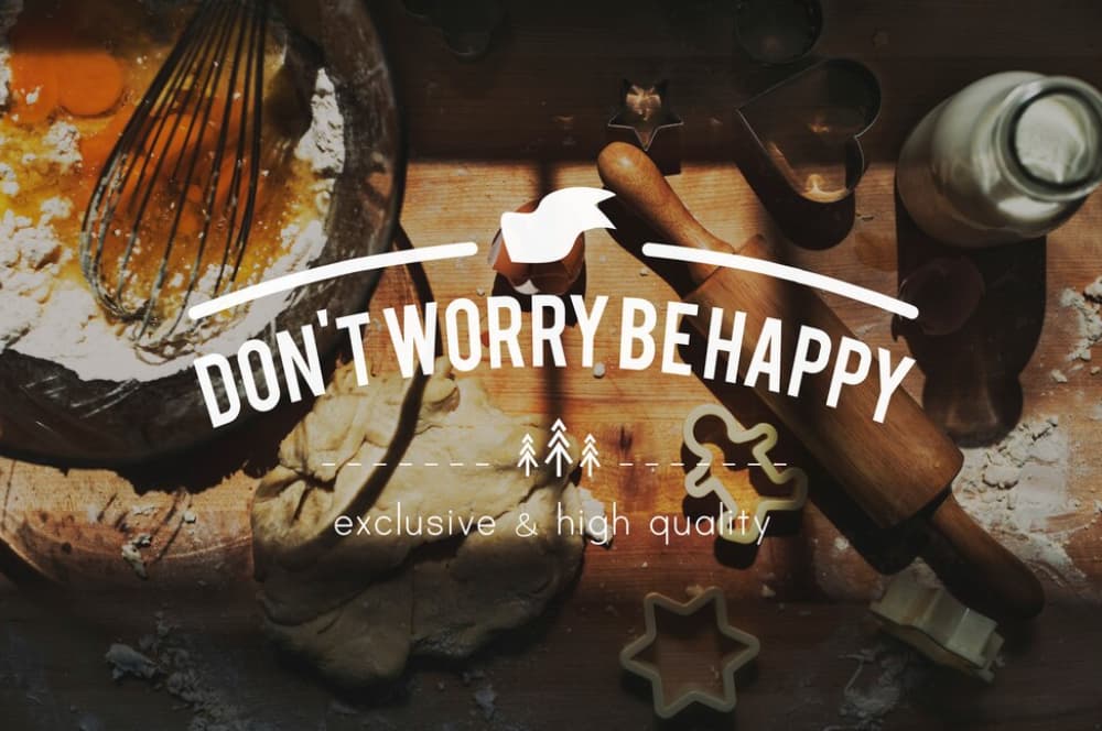 A bowl of dough with baking ingredients and rolling pin and words don't worry be happy on the picture